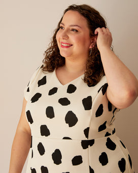 Woman wearing a white dress with black polka dots against a plain background. This dress is the Foxhill Dress sewing pattern from "Ahead of the Curve" by Jenny Rushmore.