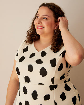 Woman wearing a white dress with black polka dots against a plain background. This dress is the Foxhill Dress sewing pattern from "Ahead of the Curve" by Jenny Rushmore.