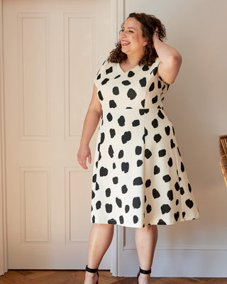 Woman wearing a black and white polka dot dress indoors. This dress is the Foxhill Dress sewing pattern from "Ahead of the Curve" by Jenny Rushmore.