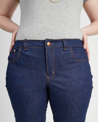 Person wearing blue jeans and a gray top on a light gray background. These jeans are the Ames Jeans sewing pattern from Cashmerette.