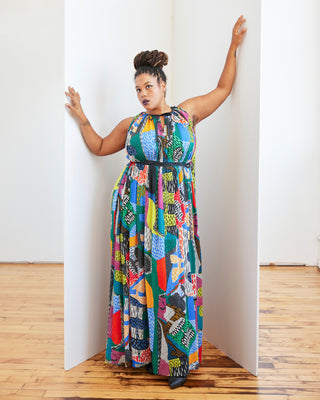 Woman wearing a colorful patterned dress standing against a white wall. This dress is the Rockwell Dress sewing pattern from Cashmerette.