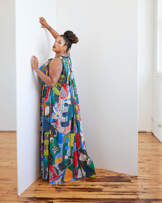 Woman in a colorful patterned dress standing against a white wall. This dress is the Rockwell Dress sewing pattern from Cashmerette.