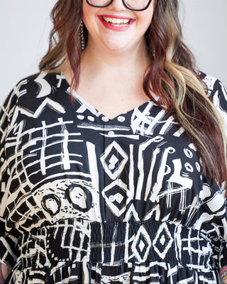 Person wearing a black and white patterned dress with a plain background. This dress is the Franconia Dress sewing pattern from Cashmerette.
