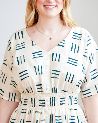 Woman wearing a white dress with blue geometric patterns against a plain background. This dress is the Franconia Dress sewing pattern from Cashmerette.