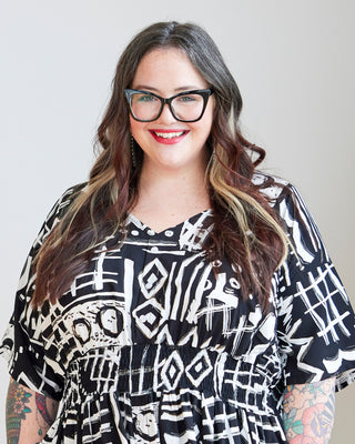 Woman wearing a black and white patterned shirt with glasses and red lipstick. This dress is the Franconia Dress sewing pattern from Cashmerette.