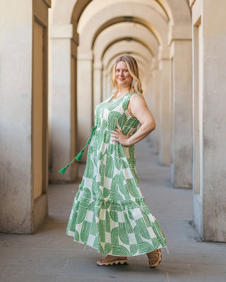 Woman in a green and white patterned dress standing in an architectural hallway. This dress is the Loring Dress sewing pattern from Cashmerette.