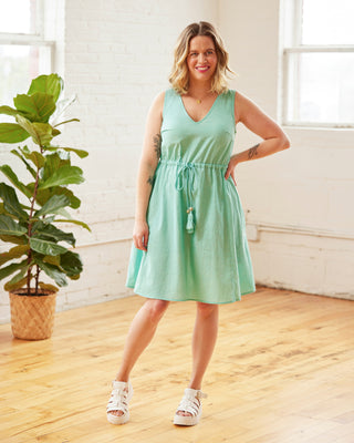 Woman wearing a light green dress standing in a room with wooden floor and large windows. This dress is the Loring Dress sewing pattern from Cashmerette.