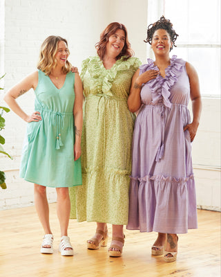 Three women wearing pastel dresses standing together in a bright room. This dress is the Loring Dress sewing pattern from Cashmerette.