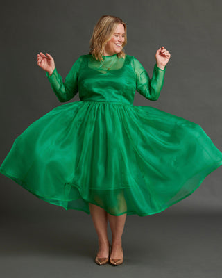 Woman wearing a green dress against a gray background. This dress is the Mansfield Dress sewing pattern from Cashmerette.