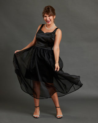 Woman in a black dress posing against a gray background. This dress is the Mansfield Dress sewing pattern from Cashmerette.