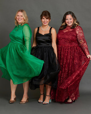 Three women in formal dresses standing against a gray background. This dress is the Mansfield Dress sewing pattern from Cashmerette.