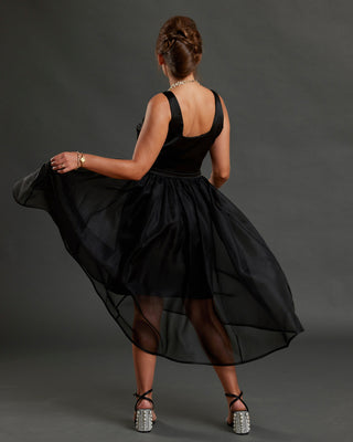 Woman wearing a black dress with sheer overlay on a dark background. This dress is the Mansfield Dress sewing pattern from Cashmerette.