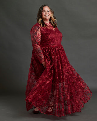 Woman wearing a red lace dress against a gray background. This dress is the Mansfield Dress sewing pattern from Cashmerette.