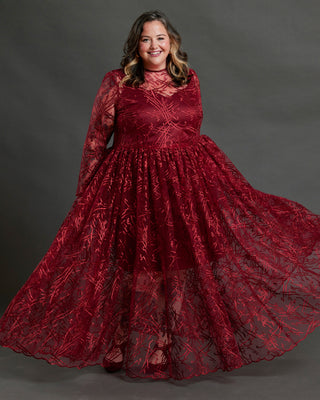 Woman wearing a red lace dress against a gray background. This dress is the Mansfield Dress sewing pattern from Cashmerette.