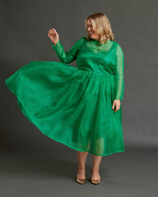 Woman wearing a green dress against a gray background. This dress is the Mansfield Dress sewing pattern from Cashmerette.