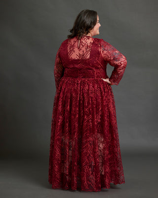 Woman wearing a red lace dress against a gray background. This dress is the Mansfield Dress sewing pattern from Cashmerette.