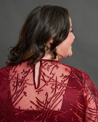 Woman wearing a red beaded dress against a gray background. This dress is the Mansfield Dress sewing pattern from Cashmerette.