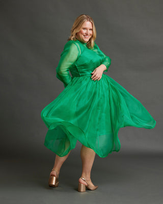Woman wearing a green dress against a gray background. This dress is the Mansfield Dress sewing pattern from Cashmerette.