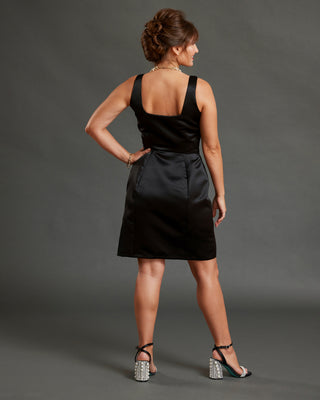 Woman wearing a black dress against a gray background. This dress is the Mansfield Dress sewing pattern from Cashmerette.