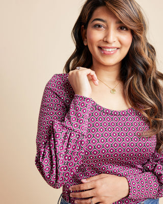 Woman wearing a patterned pink blouse against a beige background. This is the Grafton Dress, Top & Skirt sewing pattern from Cashmrette.