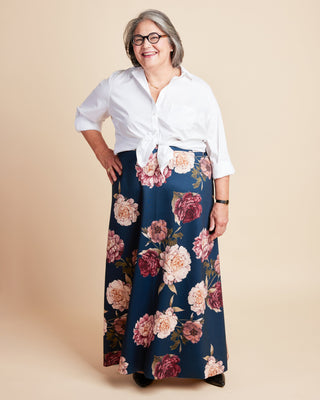 Woman wearing a white blouse and floral skirt on a beige background. This is the Grafton Dress, Top & Skirt sewing pattern from Cashmerette.