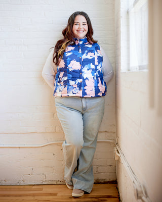 Woman wearing a floral puffer vest standing against a white wall. This vest is the Murcot Puffer Vest sewing pattern from Cashmerette.