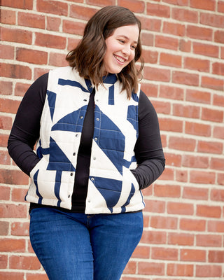 Woman wearing a patterned vest against a brick wall. This vest is the Murcot Puffer Vest sewing pattern from Cashmerette.
