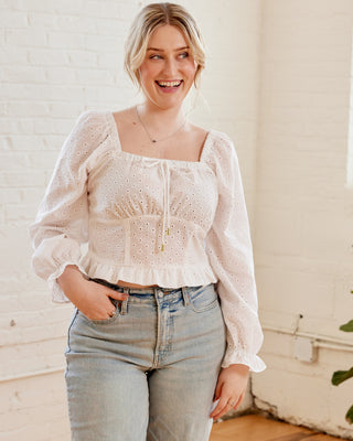 Woman wearing a white blouse with long sleeves and blue jeans indoors. This top is the Briarwood Top sewing pattern from Cashmerette.