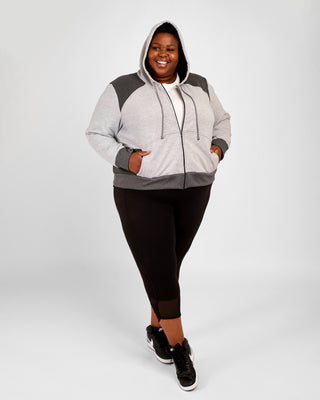 Person wearing a gray hoodie with a hood and black leggings on a white background. This hoodie is the Stanton Hoodie sewing pattern from Cashmerette.