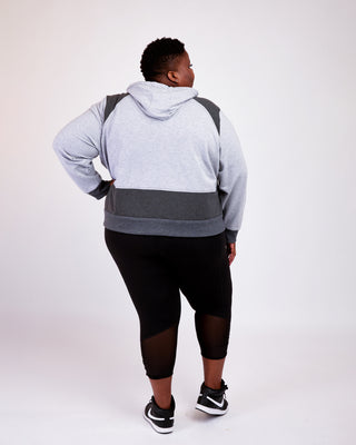 Person wearing a gray and black color-blocked hoodie on a white background. This hoodie is the Stanton Hoodie sewing pattern from Cashmerette.