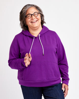 Person wearing a purple hoodie on a white background. This hoodie is the Stanton Hoodie sewing pattern from Cashmerette.