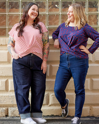Two women standing on stone steps wearing casual outfits with blue jeans. This top is the Brattle Twist Top sewing pattern from Cashmerette.