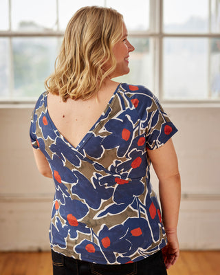 Woman wearing a blue floral patterned top in a room with large windows. This top is the Kenwin Raglan T-Shirt sewing pattern from Cashmerette.