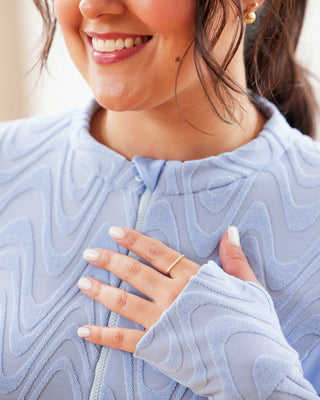 Woman wearing a light blue textured sweater with a blurred background. This top is the Bonair Athletic Top sewing pattern from Cashmerette.