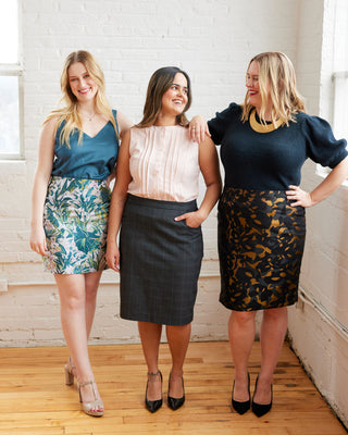 Three women standing together wearing stylish outfits in a bright room. This skirt is the Elmwood Pencil Skirt sewing pattern from Cashmerette.