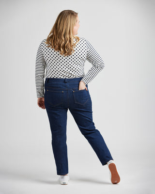 Woman wearing a polka dot top and blue jeans on a plain background. These jeans are the Ames Jeans sewing pattern from Cashmerette.