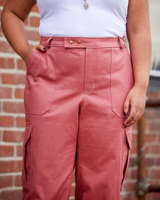 Person wearing pink pants and a white top against a brick wall. These pants are the Esmond Cargo Pants sewing pattern from Cashmerette.