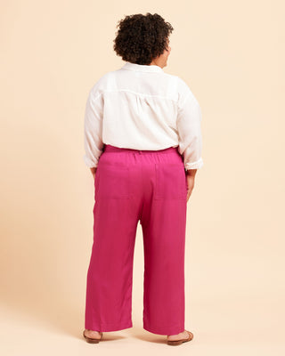 Person wearing a white shirt and pink pants on a beige background. These pants are the Everett Pants & Shorts sewing pattern from Cashmerette.
