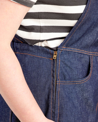 Close-up of a person wearing a blue denim apron over a striped shirt. These overalls are the Rhinecliff Overalls sewing pattern from Cashmerette.