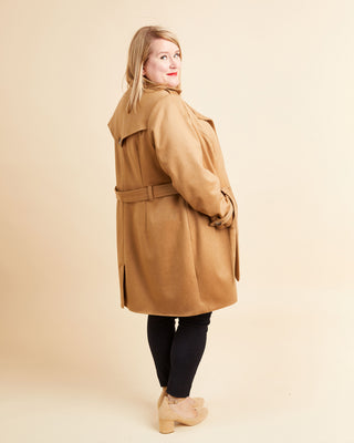 Woman wearing a tan coat on a beige background. This coat is the Chilton Trench Coat sewing pattern from Cashmerette.