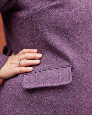 Close-up of a person wearing a purple coat with a hand on the pocket. This coat is the Newcomb Car Coat sewing pattern from Cashmerette.