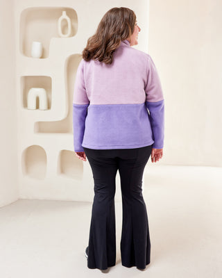 Person wearing a two-tone purple fleece jacket in a minimal indoor setting. This jacket is the Hatton Fleece Jacket sewing pattern from Cashmerette.