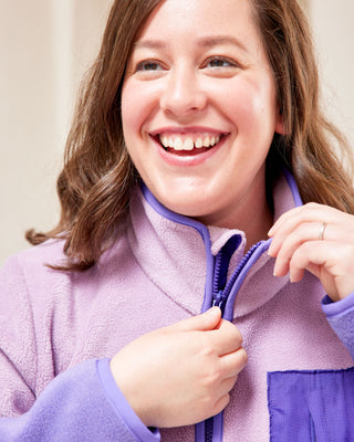 Woman wearing a purple fleece jacket with a visible brand logo. This jacket is the Hatton Fleece Jacket sewing pattern from Cashmerette.