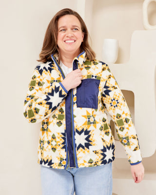 Woman wearing a colorful patterned jacket indoors. This jacket is the Hatton Fleece Jacket sewing pattern from Cashmerette.