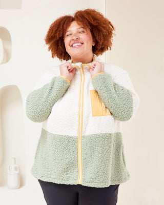 Person wearing a green and white fleece jacket with a yellow zipper, standing against a light background. This jacket is the Hatton Fleece Jacket sewing pattern from Cashmerette.