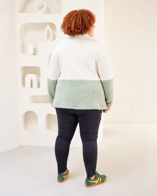 Person wearing a two-tone sweater with a white and green design, standing in front of a white wall. This jacket is the Hatton Fleece Jacket sewing pattern from Cashmerette.