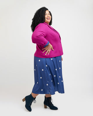 Woman wearing a pink jacket and blue polka dot skirt on a white background. This blazer is the Auburn Blazer sewing pattern from Cashmerette.