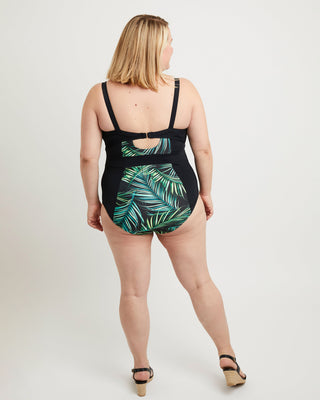 Woman wearing a black swimsuit with green leaf pattern on a white background. This swimsuit is the Ipswich Swimsuit sewing pattern from Cashmerette.