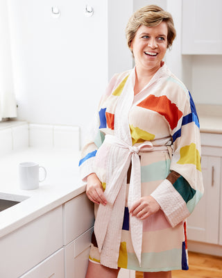 Woman wearing a colorful robe in a kitchen.  This robe is the Lygon Robe sewing pattern from Cashmerette.