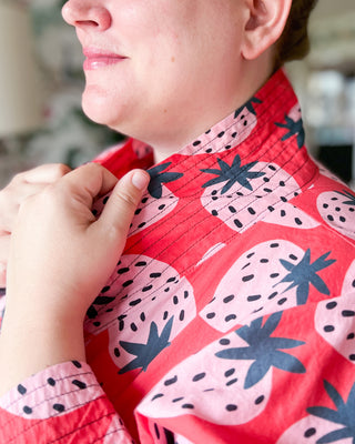 Woman wearing a robe with blue and pink fruit pattern. This robe is the Lygon Robe sewing pattern from Cashmerette.